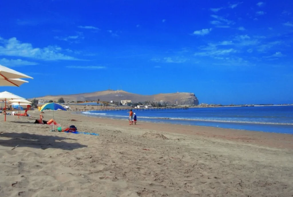 Amplia vista de una playa tranquila con arena dorada y un cielo despejado, ideal para relajarse y disfrutar del mar.