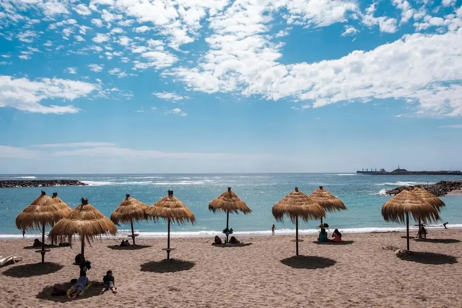 Vista de la playa con sombrillas y cielo despejado cerca del Hotel Casa Beltrán en Arica.