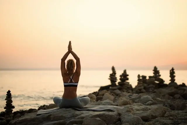 mujer practicando yoga en la playa
